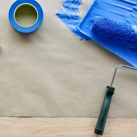ScotchBlue™ Abdeckband neben einem Pinsel, der mit blauer Farbe bedeckt ist