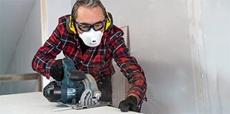 Mann trägt Sicherheits-PSA beim Schleifen von Holz
