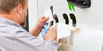 Mann bringt Beschriftungen auf einem Auto an
