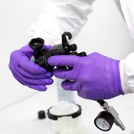 Hände mit violetten Handschuhen setzen einen Düsenkopf auf die 3M Hochleistungslackierpistole