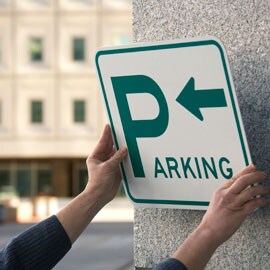 Person, die ein Parkplatzschild an einer Betonwand befestigt
