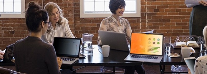 Personen, die am Tisch über Laptop-Bildschirme zusammenarbeiten, auf denen vertrauliche Daten angezeigt werden
