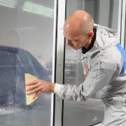 Mann bringt die Dirt Trap Kabinenschutzfolie an einem Fenster mit einem Spachtel an
