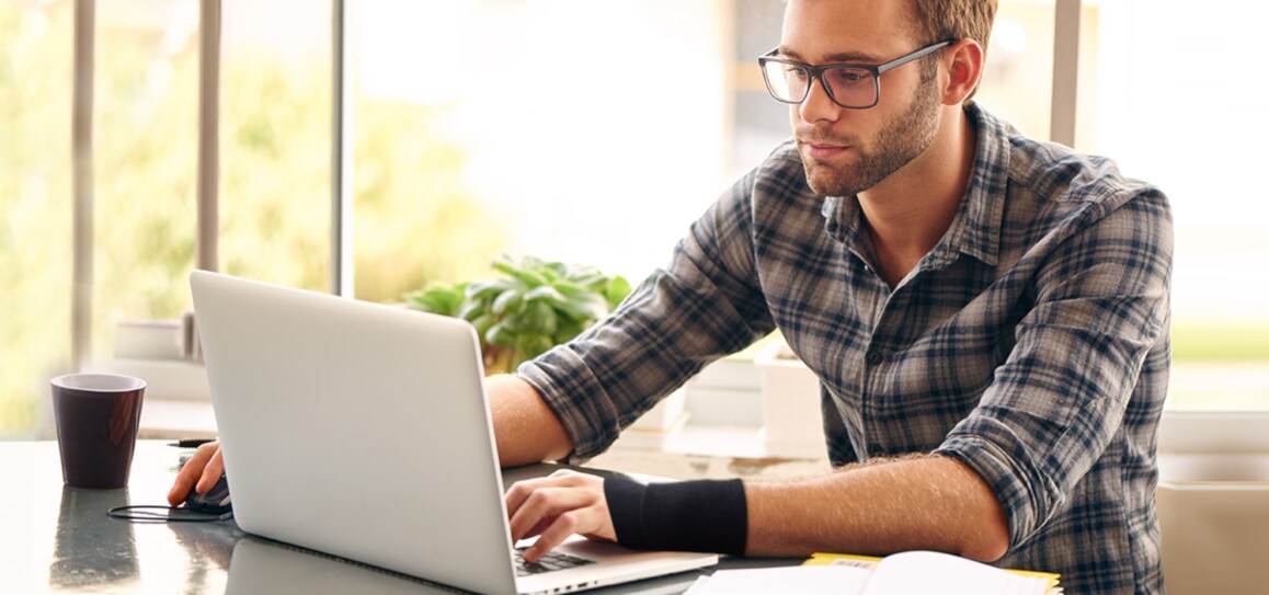 Mann bei der Arbeit am Laptop mit angelegter Handgelenkstütze