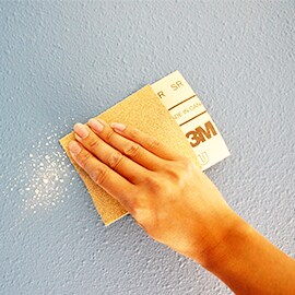 Entfernen Sie Unebenheiten mit Schleifpapier.