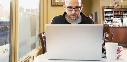 Person, die in der Öffentlichkeit an einem Laptop arbeitet

