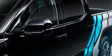 Details einer leuchtend blauen und weißen Akzentfolierung auf einem schwarzen Pickup-Wagen.
