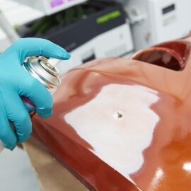 Besprühen eines beschädigten Stoßstangenbereichs mit Haftvermittler