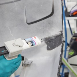 Tragen Sie mit einer Handdruckpistole Reparaturmasse für flexible Teile auf die Rückseite des Risses auf und verteilen Sie sie.