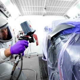 Ein Lackierer lackiert eine Auto-Oberfläche mit einer 3M Hochleistungslackierpistole