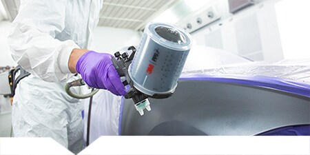 Lackierer lackiert ein repariertes Karosserieteil
