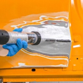 Techniker trägt 3M™ Epoxidharz Zinnersatz-Spachtelmasse auf, um die Delle auszufüllen