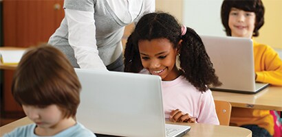 Kinder in einem Klassenzimmer an Laptops
