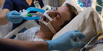 Patient in der Intensivpflege, der von medizinischem Personal betreut wird

